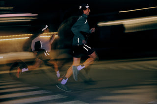 Runner on a city street at night, lit from behind by headlights